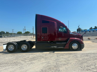 Kenworth T680 semi-truck side view, deep red cab with sleeper, black chassis, three rear axles, chrome wheels.