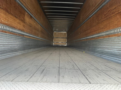 Trailer interior showing empty dry van cargo space with wooden side walls and metal ribs.