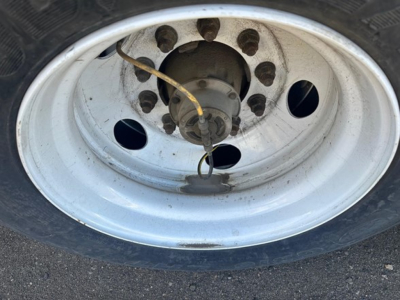 Wheel and tire close-up on a Hyundai air ride dry van trailer showing a metallic rim with lug nuts and a yellow cable/air line near the hub.