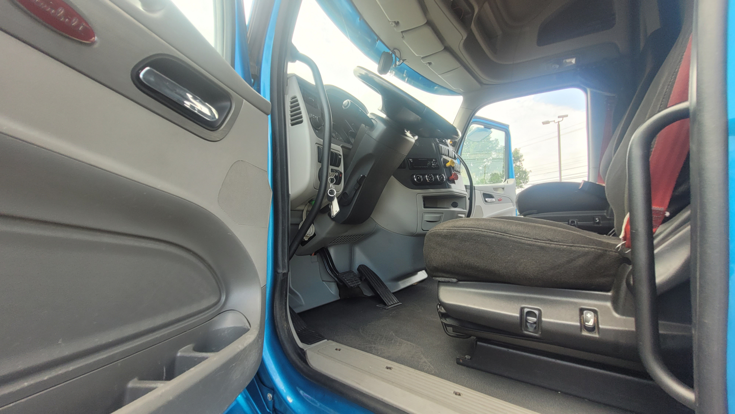 Peterbilt 579 cab interior showing driver seat and dashboard from open door.