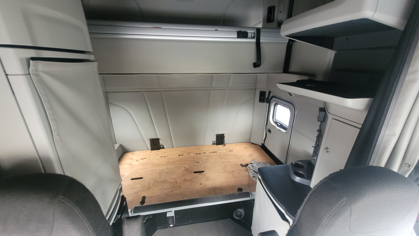 Peterbilt 579 cab interior showing sleeper area and storage shelves.