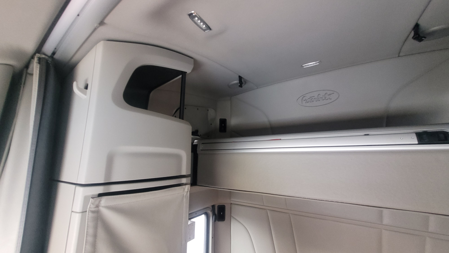 Peterbilt 579 cab interior showing sleeper area with overhead storage and dash area.