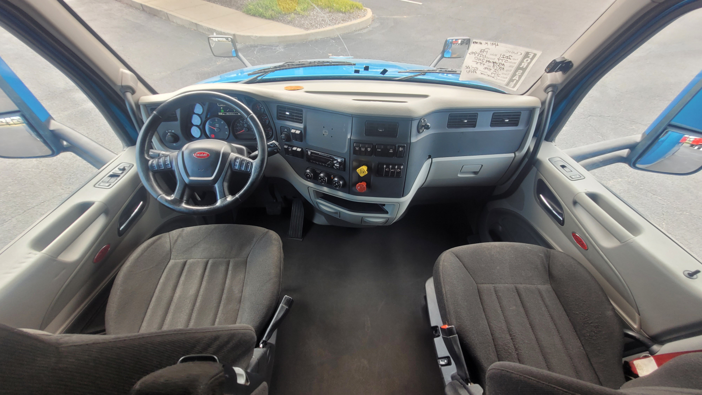 Peterbilt 579 cab interior showing dashboard, steering wheel, and front seats.