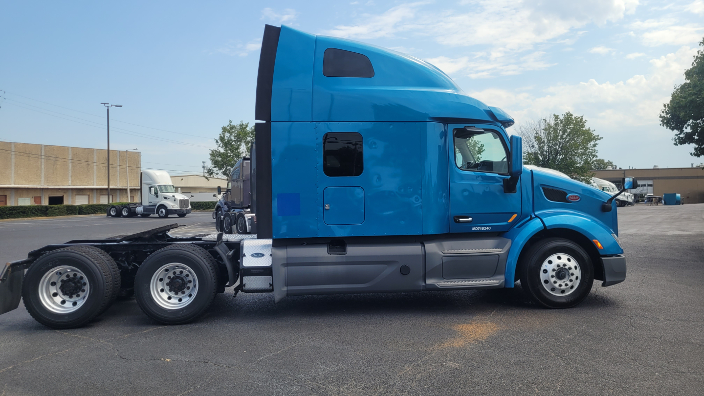 Peterbilt 579 sleeper cab truck side view showing blue paint, chassis, and rear axle; visible wheel rims and side mirrors.