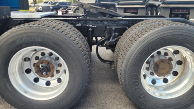 Dual rear axles of a Peterbilt truck chassis with large tires and rims; some rust on the hub areas; undercarriage components visible.
