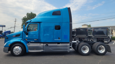 Peterbilt 579 sleeper cab truck in blue, side view, with two rear axles and chrome wheels; several windows and a black air intake