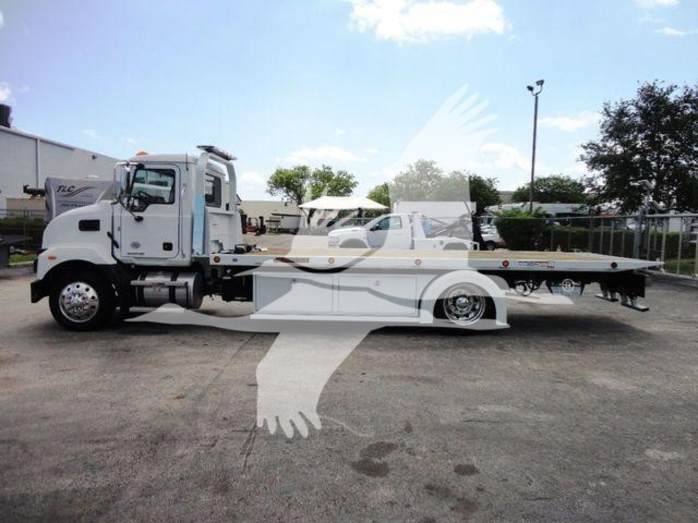 2026 Mack MD6 rollback truck in a dealership lot, side view with a long flatbed and towing equipment. Visible text on image includes none clearly readable; overall scene is a new truck with stock number J04370 in a yard.