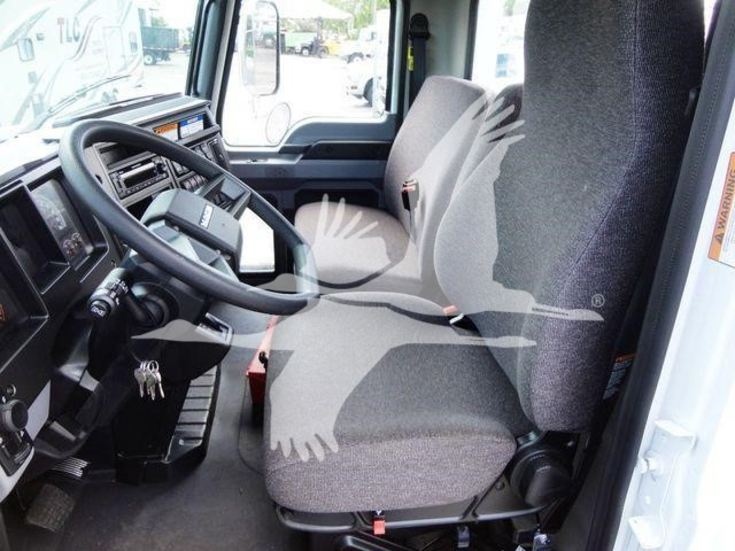MD6 truck cab interior showing steering wheel and two front seats with gray fabric, dash controls, and door frame.