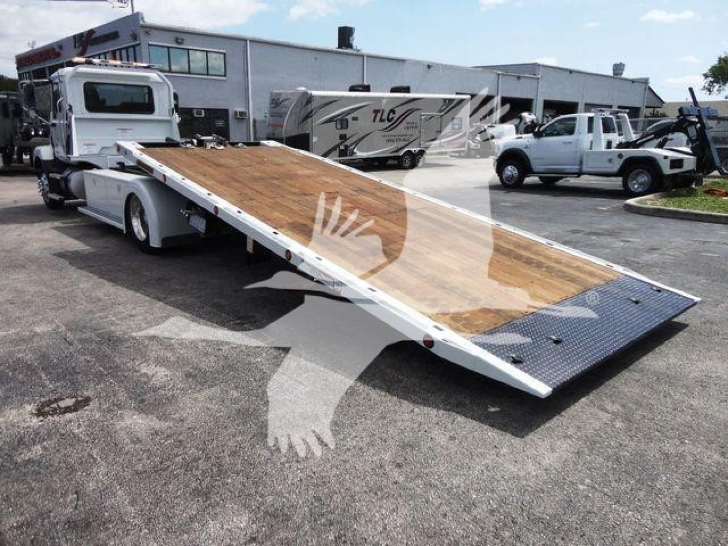 MD6 Mack rollback truck with flatbed ramp lowered, showing heavy-duty wood deck and metal ramp lip.