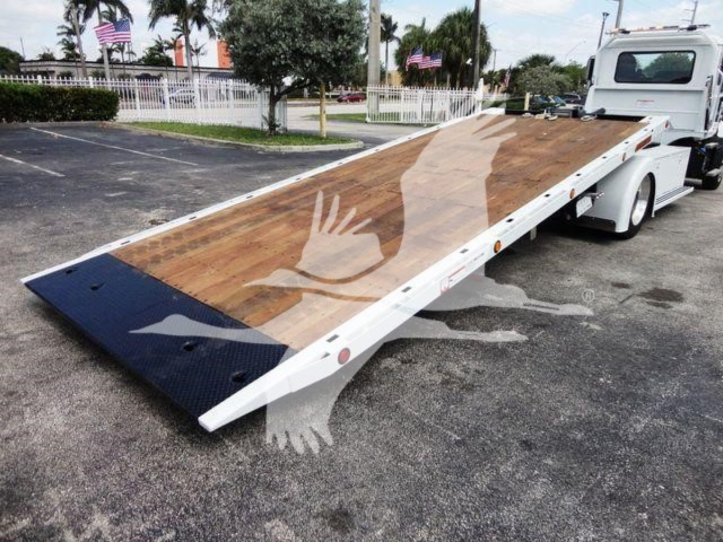 MD6 rollback truck flatbed with wooden deck and black anti-slip sections at the end, white cab, parked in lot