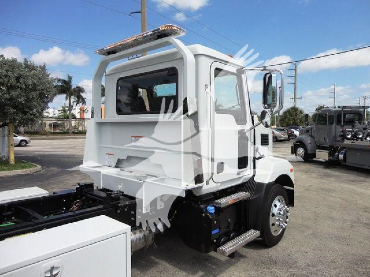 Truck cab rear and side view showing a white Mack MD6 rollback truck with black chassis, chrome exhaust, and rear window. Visible text on badges includes Mack logo and model styling.