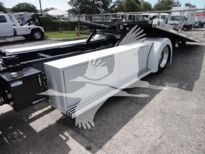 Flatbed tow truck chassis of a 2026 Mack Md6 rollback truck showing side panels and hydraulic system.