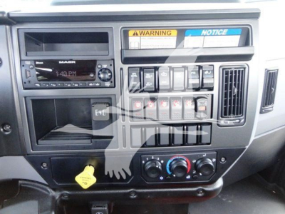 Dashboard area of a Mack MD6 truck showing radio display, control switches, hazard area, and climate controls. Visible text includes WARNING and NOTICE labels, various switch labels, and a yellow hood dipstick knob.