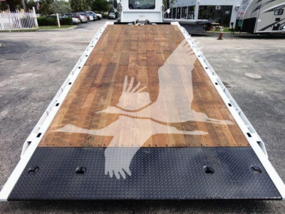 Flatbed truck deck on a 2026 Mack MD6 rollback unit showing wooden platform and black non-slip ramp area at the front.