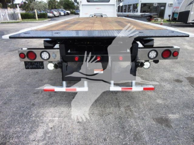 Flatbed tow truck rear view showing platform and bumper lights, license plate area, and reflective safety bars on a Mack MD6 bed.