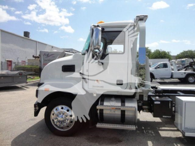 Truck cab side view of a new 2026 Mack MD6 rollback truck showing chrome wheel, side steps, and fuel tank.
