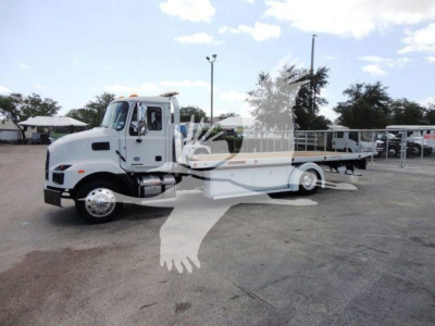 MD6 truck in service bay showing white Mack rollback wrecker, front cab and long flatbed with wheel base.