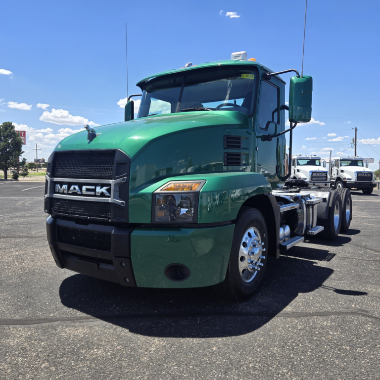 Green Mack Anthem truck in a parking lot, front-left view showing grille with MACk logo and headlights.