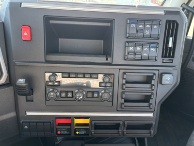 Dashboard panel of a Mack AN64T daycab showing control switches, climate controls, and storage compartments.