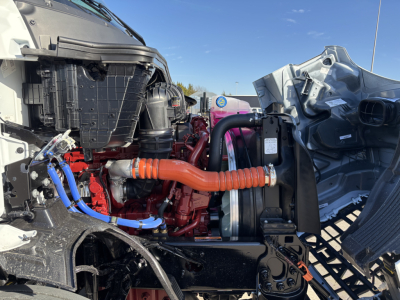 Mack AN64T engine bay showing orange diesel intake hose and blue coolant line.