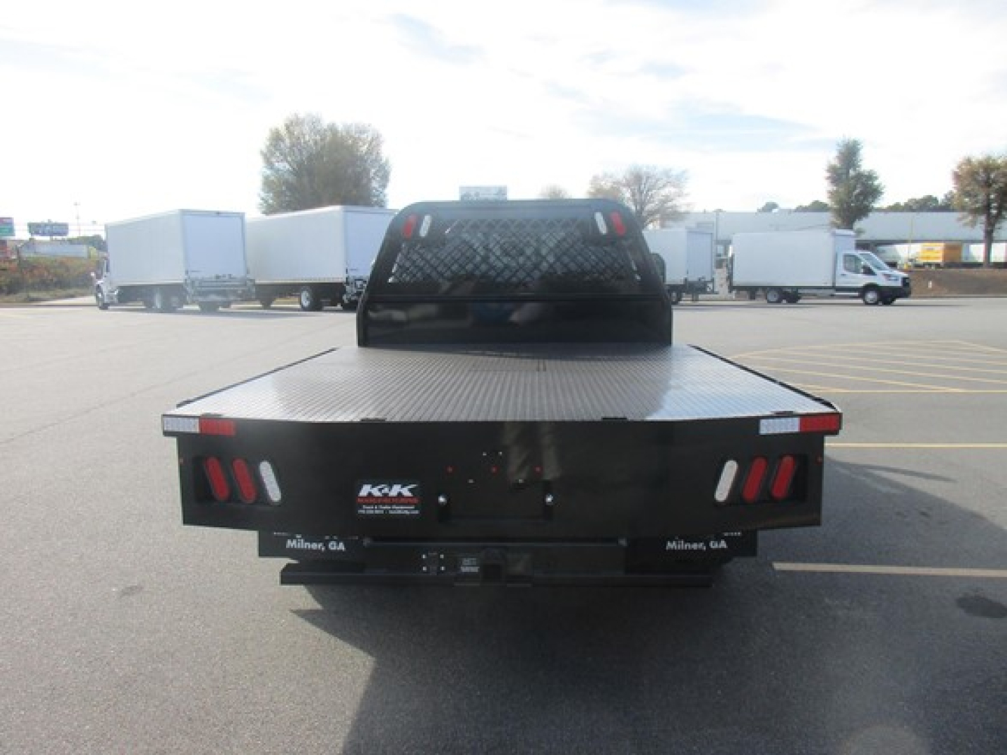 Flatbed truck bed with honeycomb headache rack and rear taillights, view from back showing Milner, GA branding plate on each side.