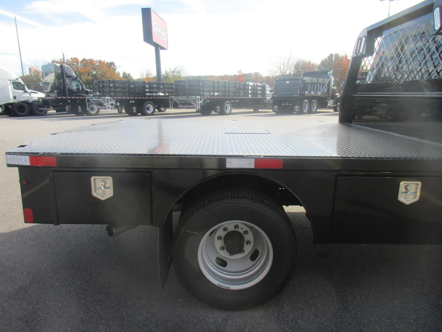 Truck flatbed showing wheel and side toolboxes with reflective markers and diamond plate bed.