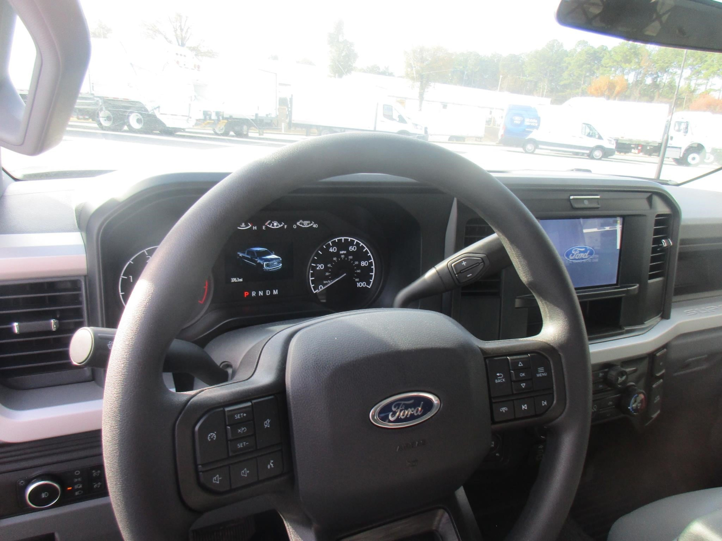 Ford F-350 interior steering wheel and dashboard with digital gauge cluster and infotainment screen.