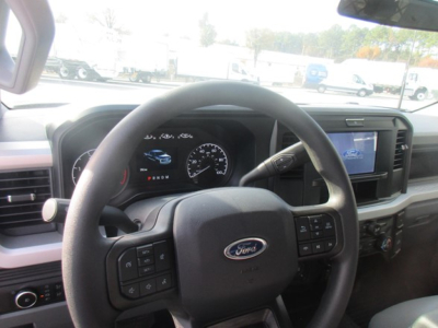 Ford F-Series dashboard interior showing steering wheel with Ford logo, instrument cluster, and media screen. Visible text includes steering wheel controls and dashboard markings.