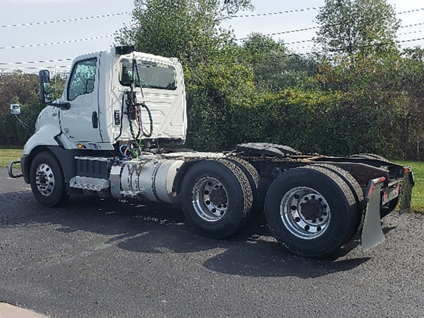 Truck chassis of a white 2019 International RH613 daycab, side view showing rear dual axle and fifth wheel area.