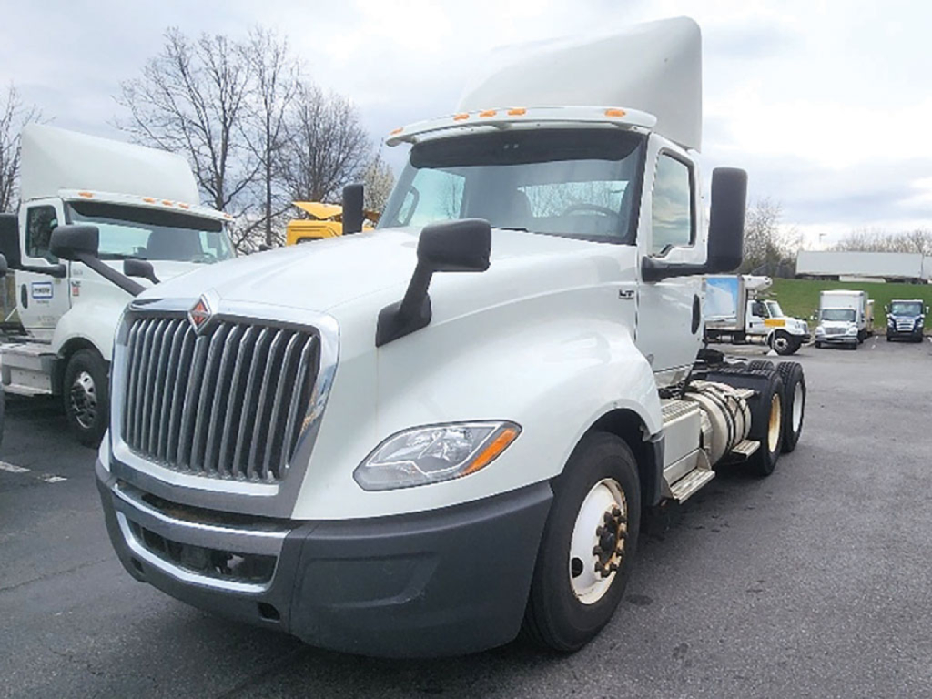 International LT625 daycab tractor showing front grille, headlights, and side mirrors with sleeper cab in background.