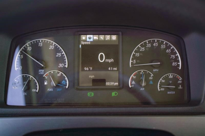 Dashboard of a Freightliner 114SD showing digital speedometer at 0 mph, with gauges for RPM, fuel, oil pressure, air, coolant, and parameters on center display.