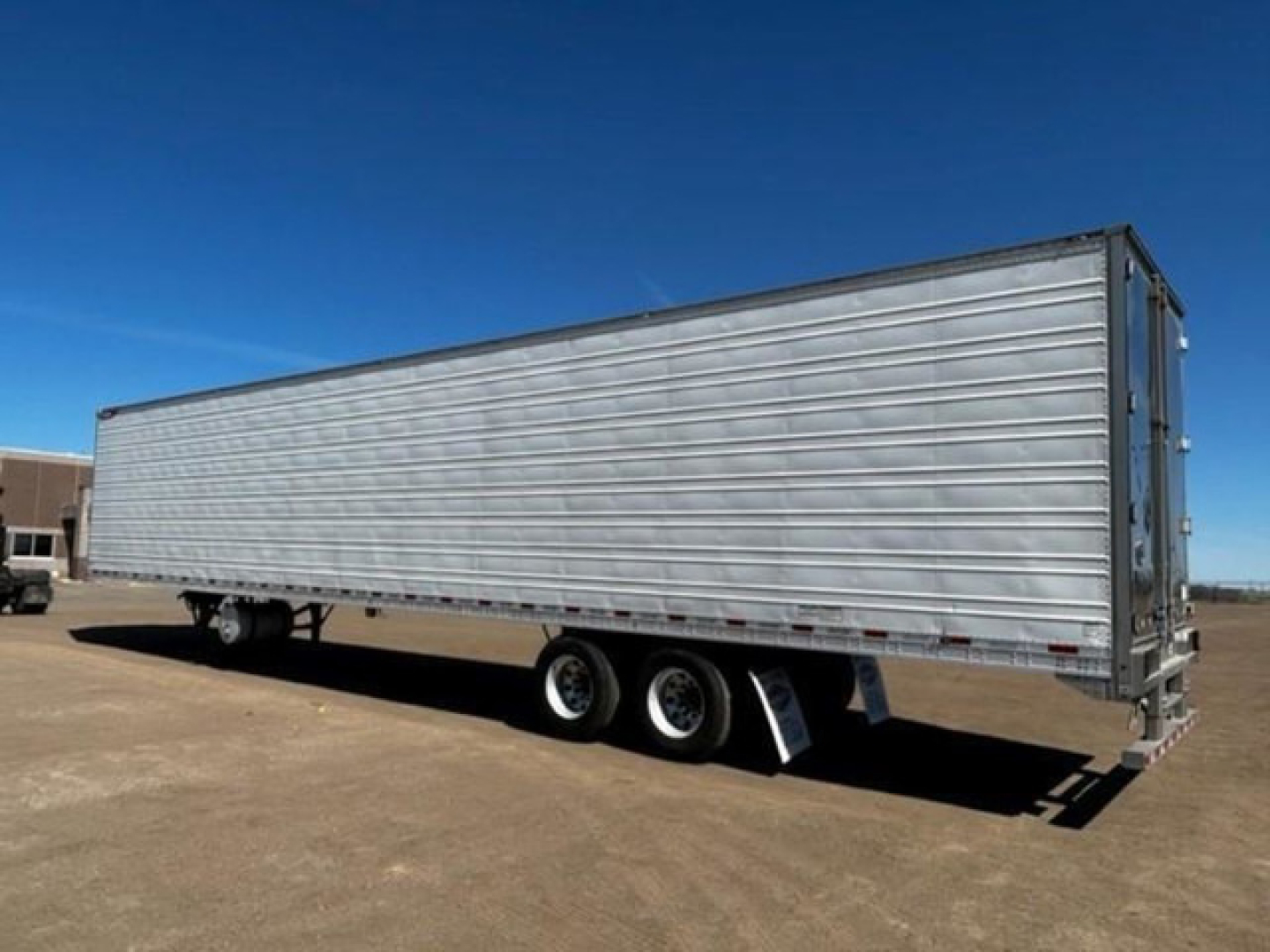 Great Dane reefer trailer in side view with triple axle and silver ribbed walls.