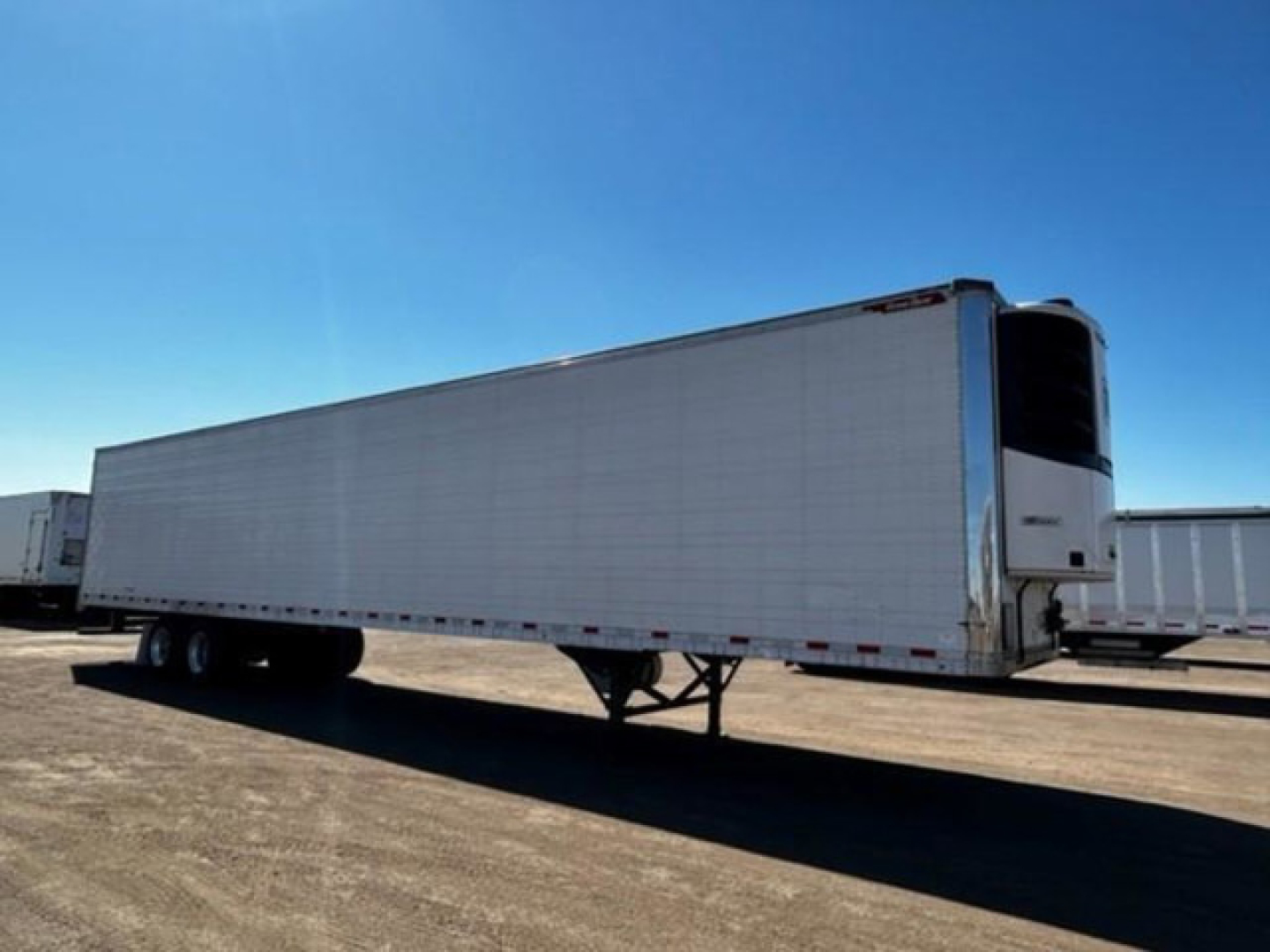 Great Dane reefer trailer in a parking lot, side view showing refrigerated unit at front, tandem axles, landing gear extended.