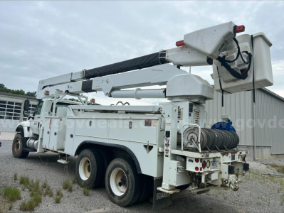 Truck bucket boom utility vehicle showing mounted utility compartment and rear hose reel with stabilizing outriggers and bucket bucket lift.