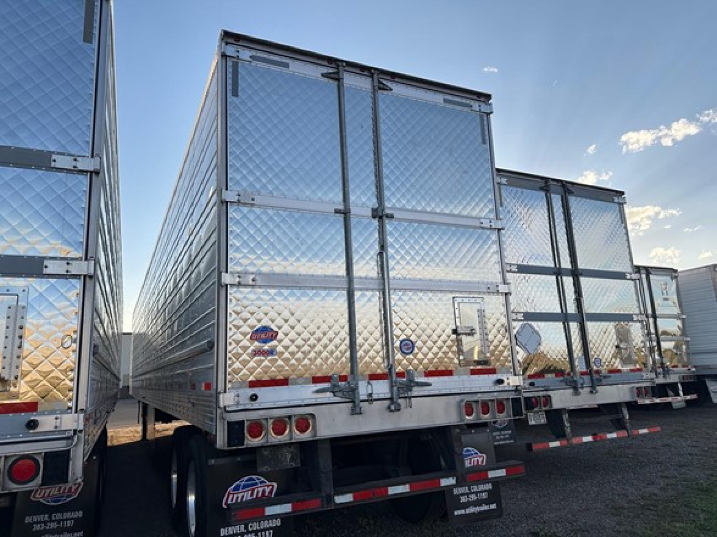 Trailer side view showing aluminum tandem axle refrigerated trailer with diamond plate exterior and rear doors