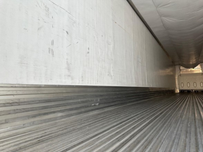 Trailer interior with ribbed metal floor and sidewall in a reefer trailer cargo area.