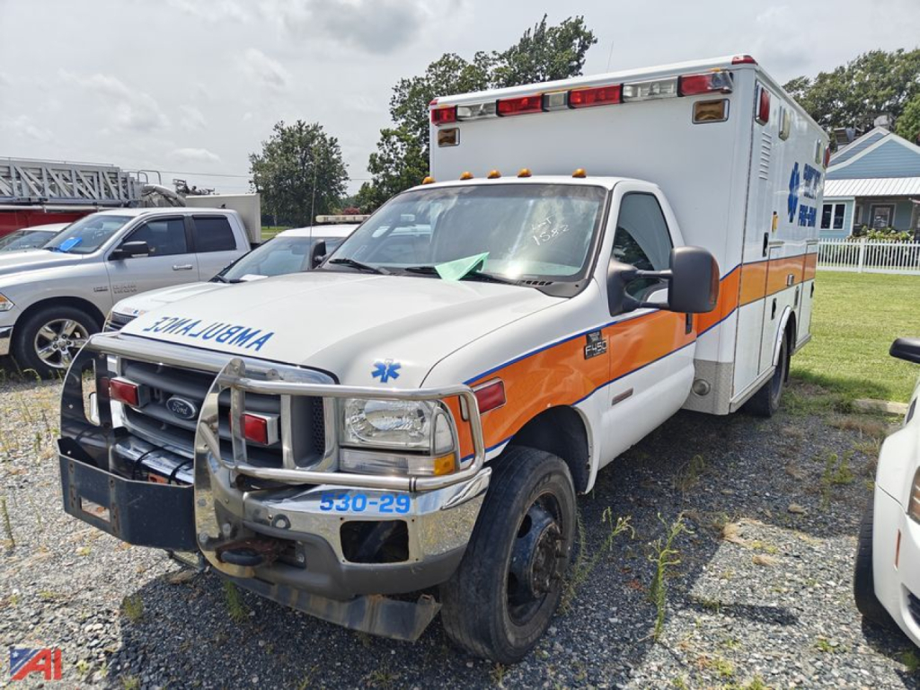 Ambulance-equipped Ford F-450 Super Duty front-left view showing orange and white livery, grille guard, and ambulance box in background.