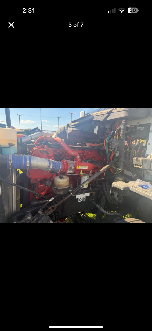 Kenworth T680 engine bay showing red engine components and various colored hoses and wiring harnesses.