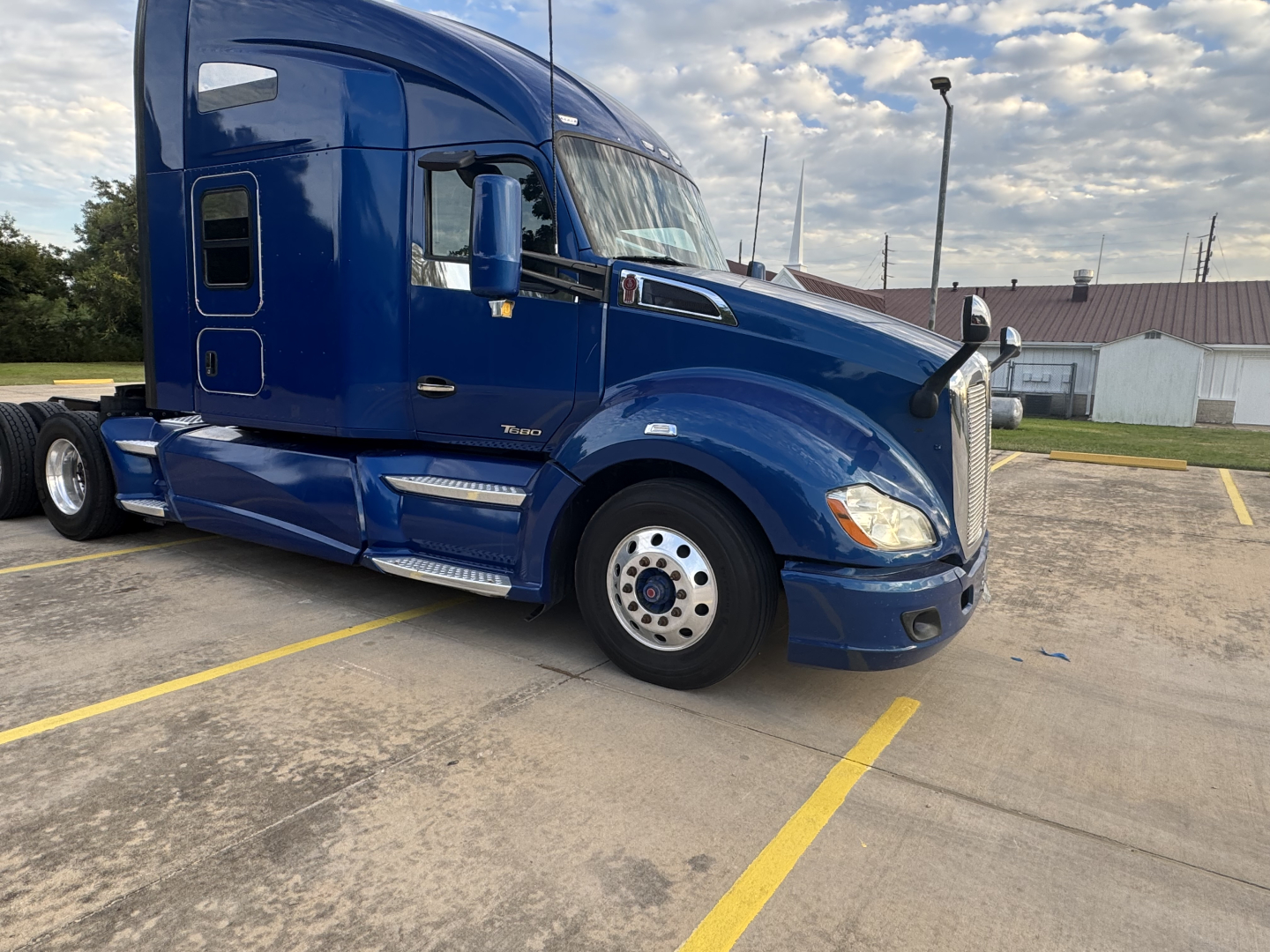 Blue 2022 Peterbilt 579 conventional sleeper truck parked in lot, front-side view showing cab, wheel, and aerodynamic mirrors.