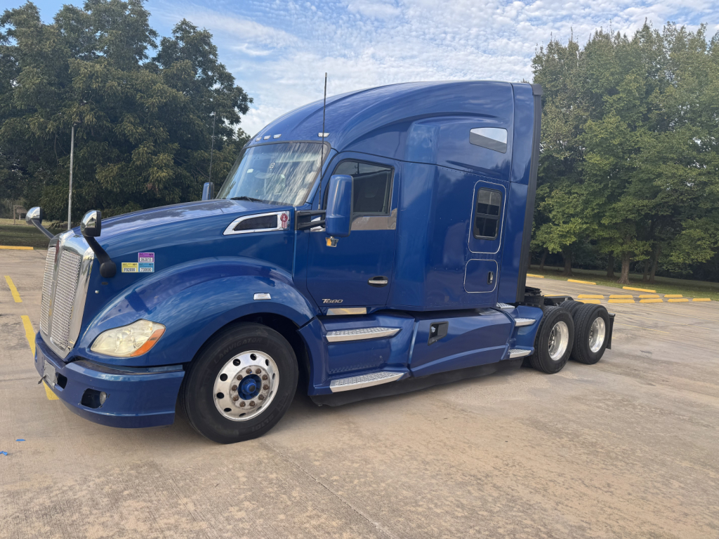 Peterbilt 579 tractor in blue, side view showing sleeper cab and triple rear axles.