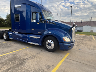 Blue 2022 Peterbilt 579 conventional sleeper truck parked in lot, front-side view showing cab, wheel, and aerodynamic mirrors.