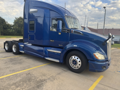 Blue Peterbilt 579 tractor unit in a parking lot, side view showing cab, front wheel, and sleeper area with no visible text.
