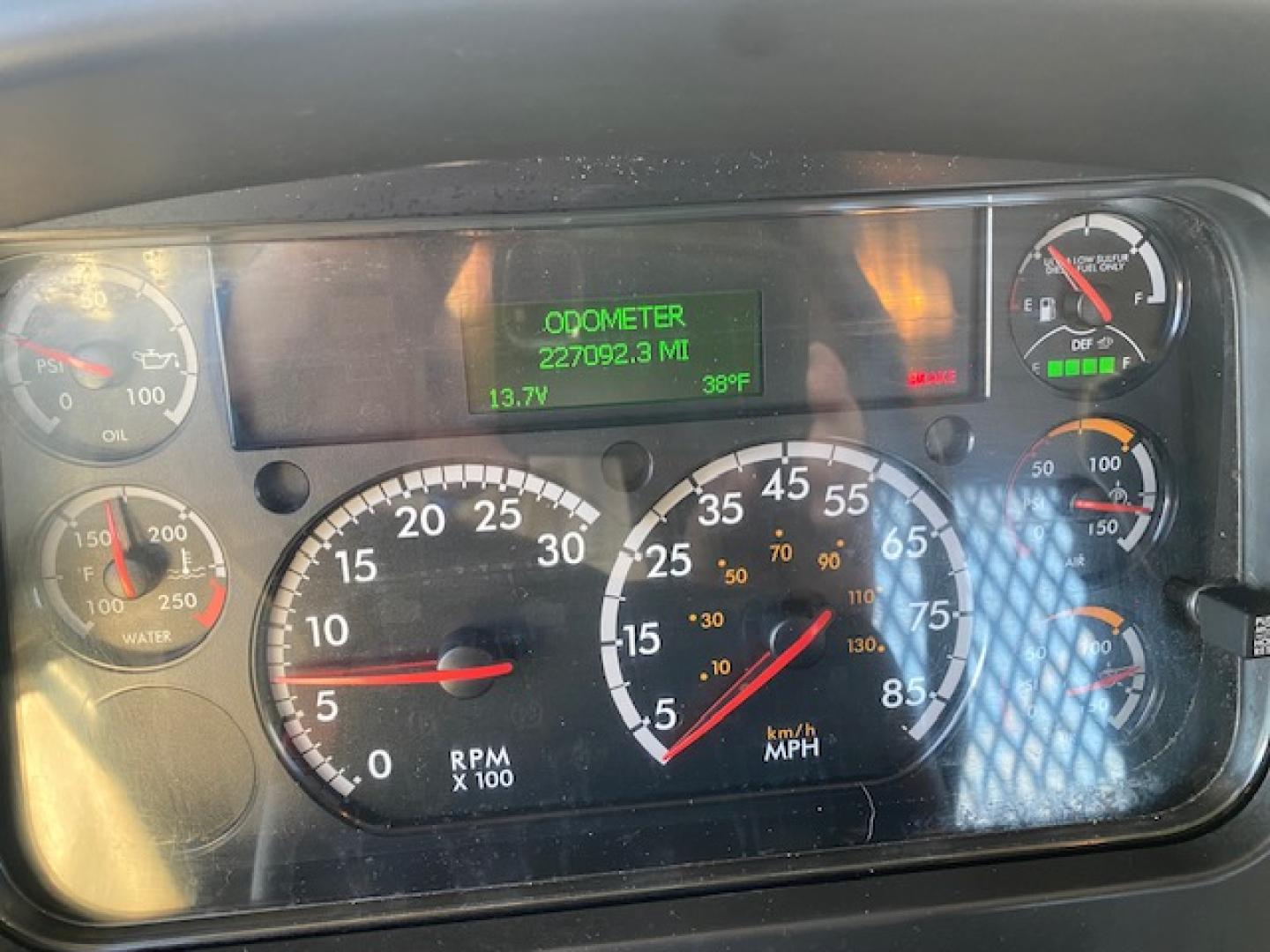 Dashboard gauge cluster of a Freightliner truck showing odometer 227,092.3 miles on green display, RPM gauge, speedometer, fuel and temperature gauges.