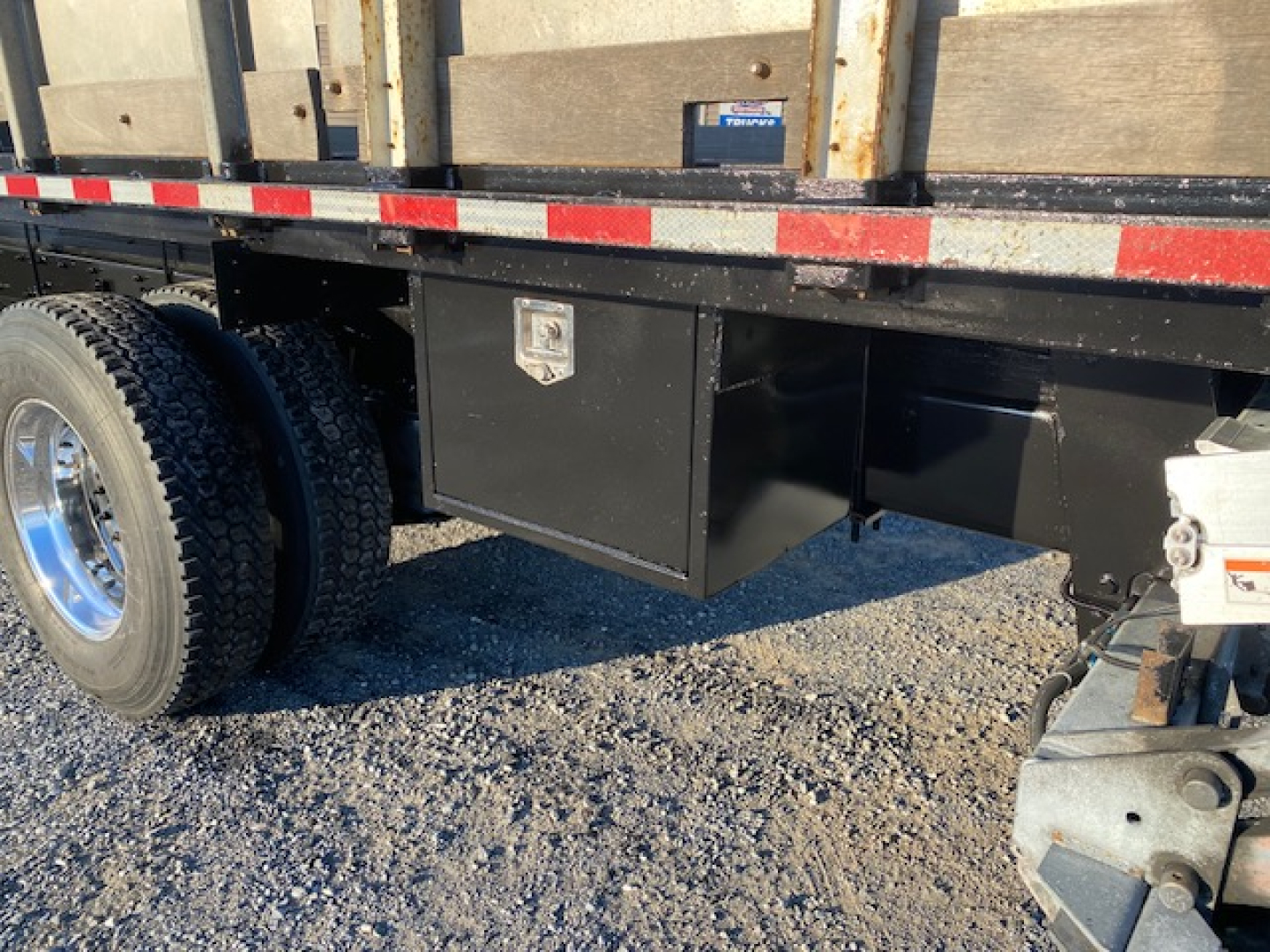Freightliner M2-106 underbody toolbox and flatbed with dual rear tires visible.