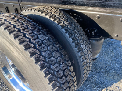 Freightliner M2-106 wheel and dual rear tires under flatbed chassis showing tire tread and wheel rims.