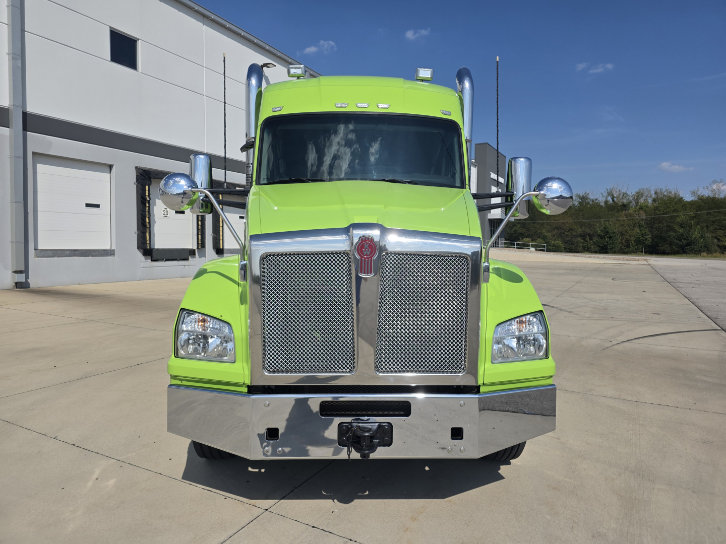 Kenworth T880 conventional sleeper truck front view in bright green showing chrome grille and bumper.