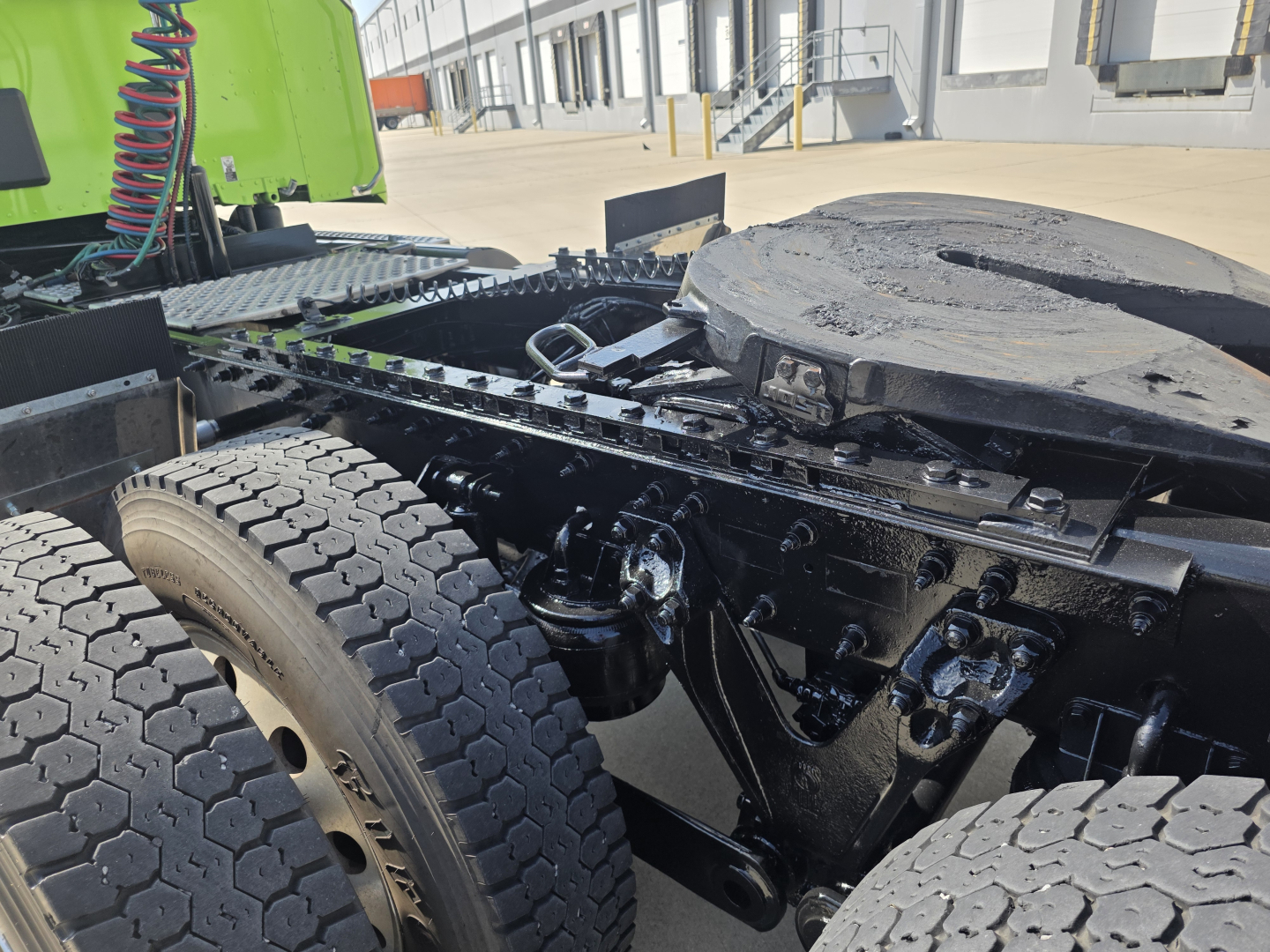 Kenworth T880 chassis view showing rear dual tires, fifth wheel, and linkage with visible suspension components.