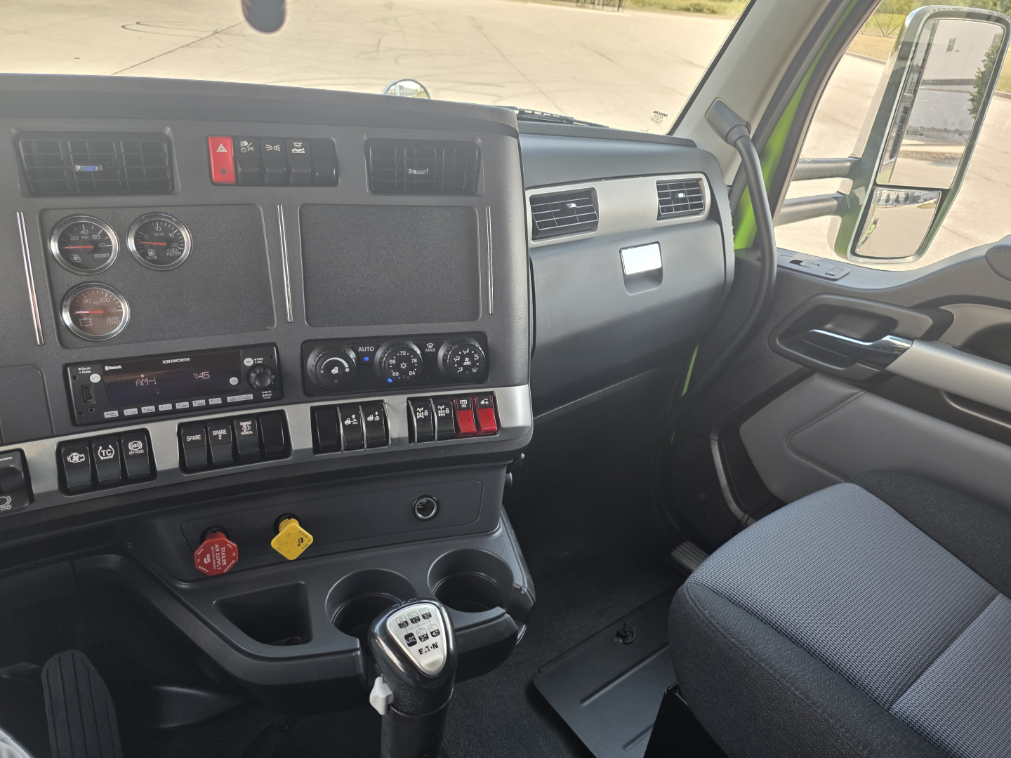 Kenworth T880 dashboard and driver seat interior showing steering wheel, gauges, and gear shifter.