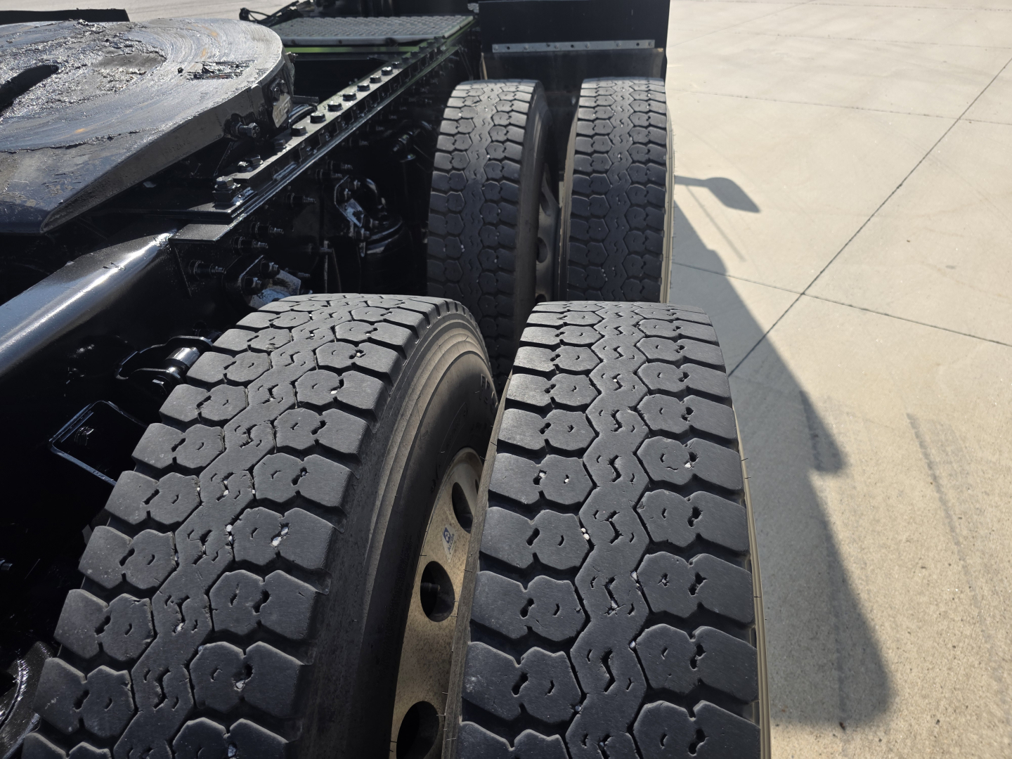 Kenworth T880 truck rear wheels and chassis view showing dual rear axles and heavy-duty tire tread.