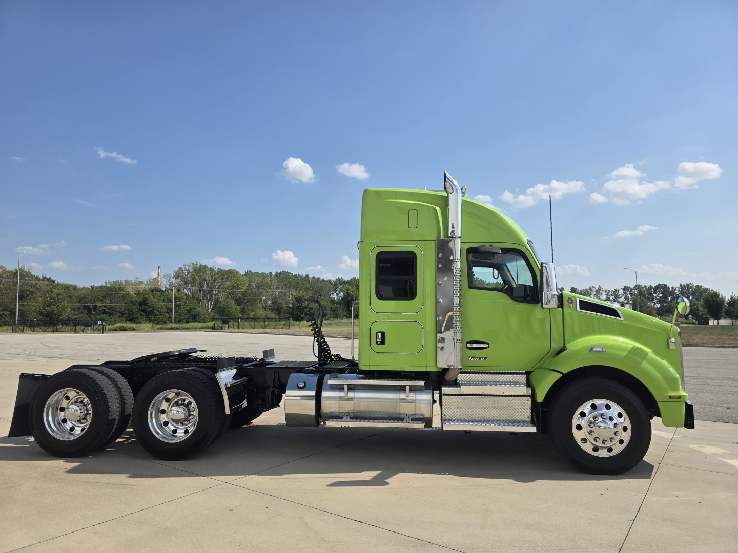 Kenworth T880 cargo tractor side view showing bright lime green sleeper cab and chassis with chrome fuel tanks and dual rear axles.